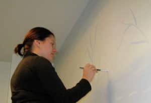 Image of Jaime holding a brush and painting on a wall